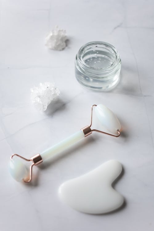 Facial massage tools arranged on marble table — jade roller gua sha set