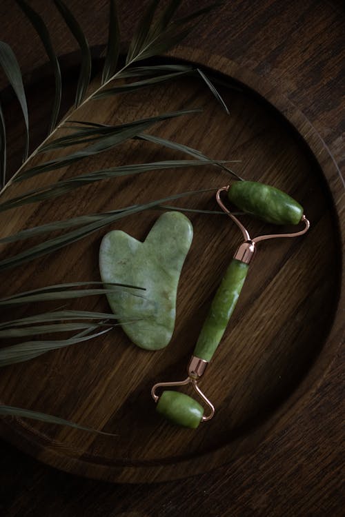 Jade roller and gua sha set on wooden surface — natural skincare tools
