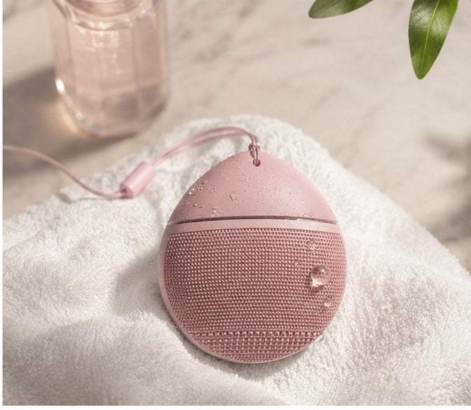 Sonic Silicone Facial Cleansing Brush on white towel with skincare products